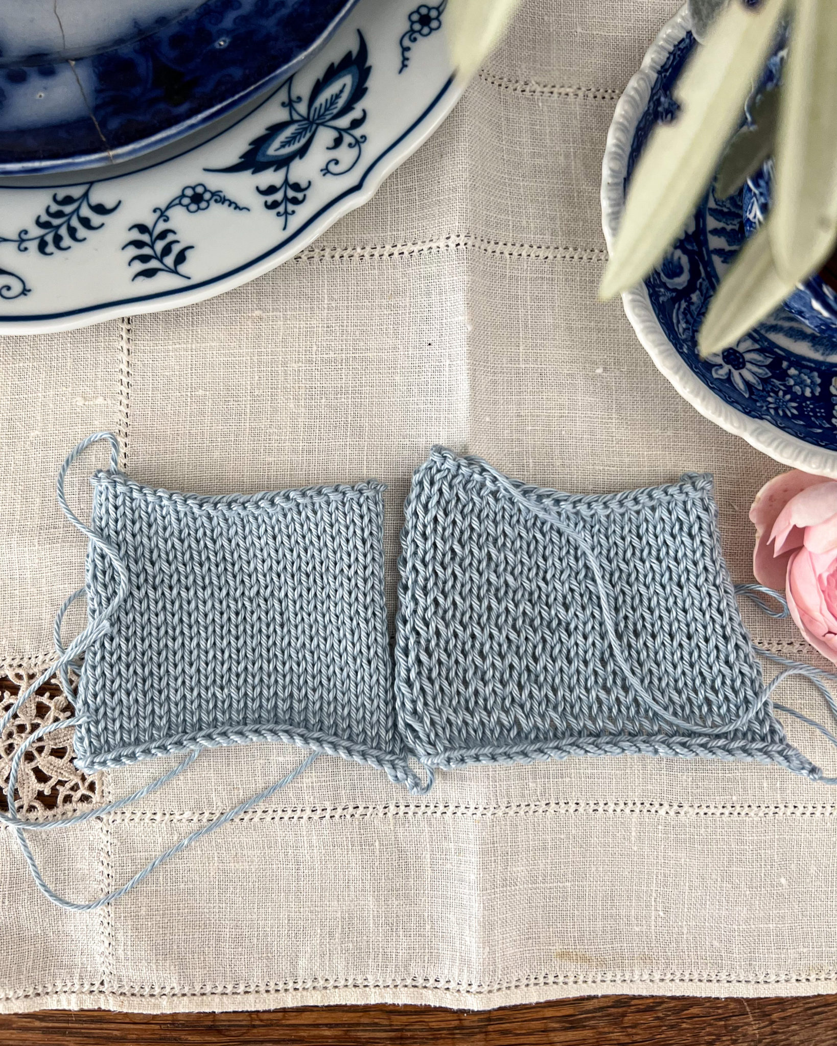 Two blue and white swatches are viewed top down with the smooth stockinette side facing up. The swatch on the left has even stitches. The swatch on the right has visible rowing out.