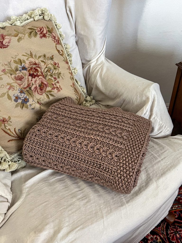 A photo of the folded Catalina Eddy Blanket on the seat of a wing-back chair