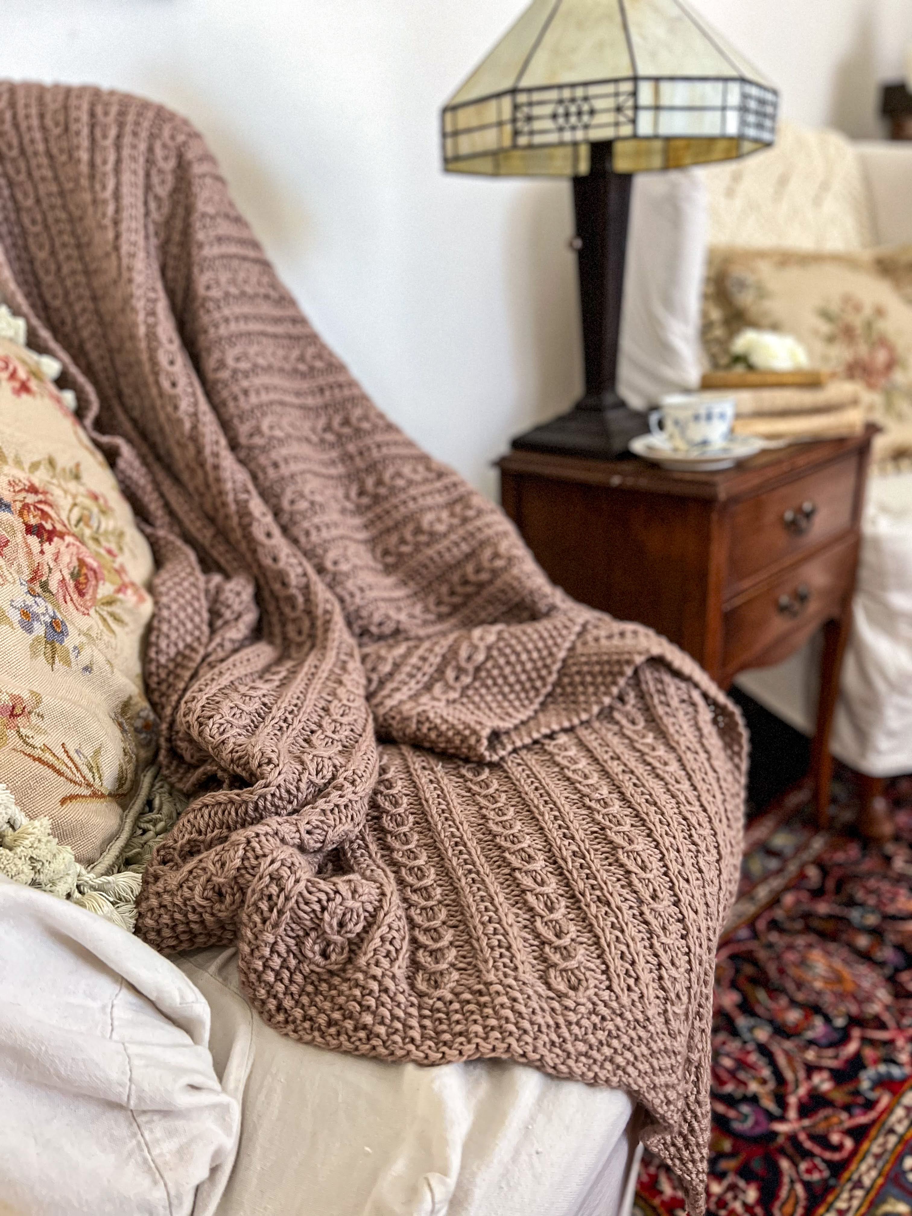 A close-up image of the Catalina Eddy Blanket draped across the arm and seat of a wing-back chair