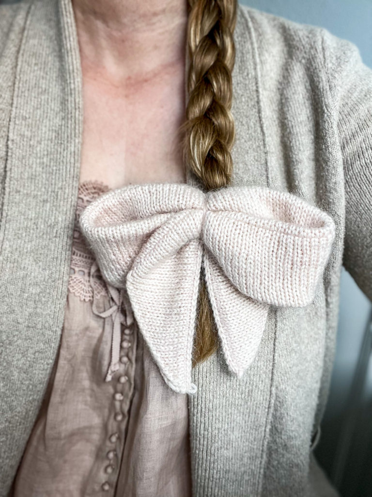 A large, pink, fuzzy hairbow attached to the end of a long, blonde braid