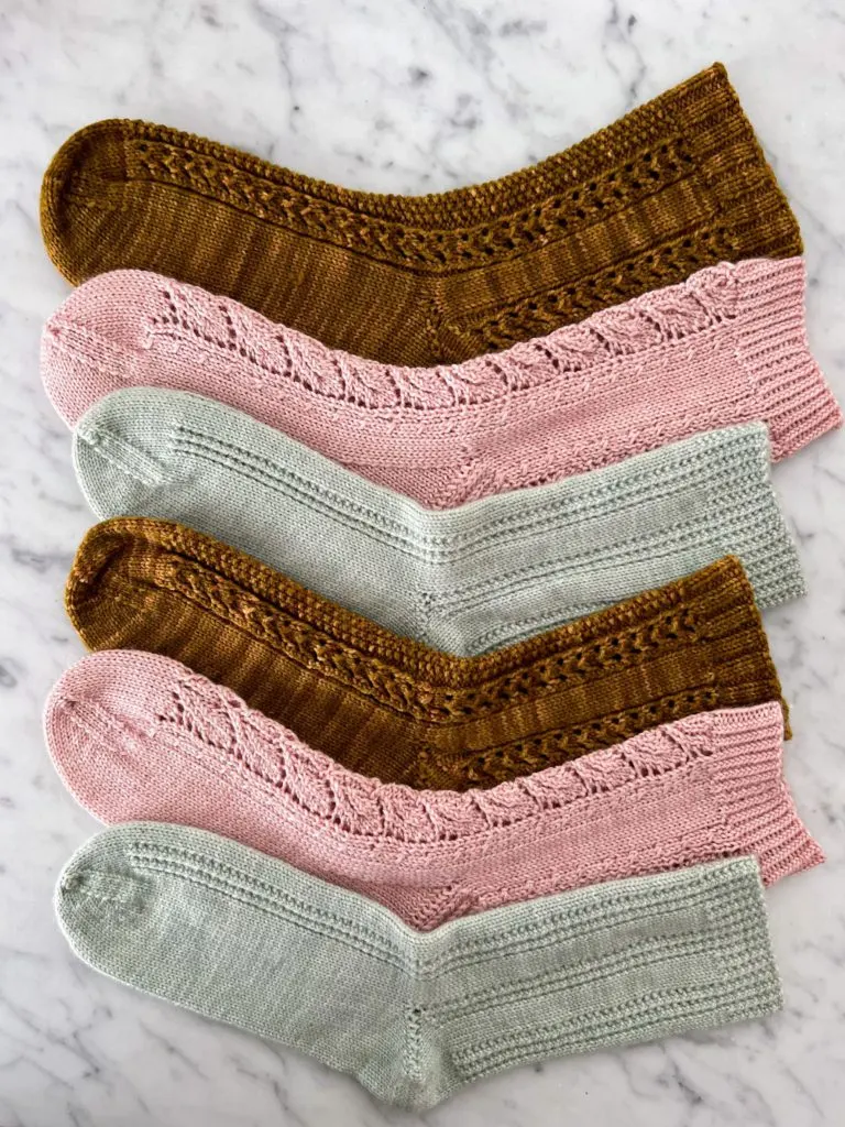 A stack of socks in alternating shades of caramel, pink, and seafoam green
