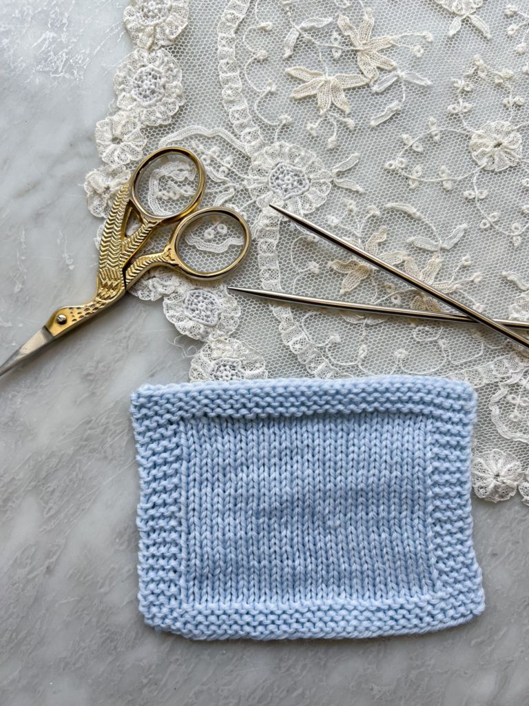 A freshly blocked swatch knit in light blue Knit Picks Stroll. The stitches have loosened up and the fabric has bloomed.