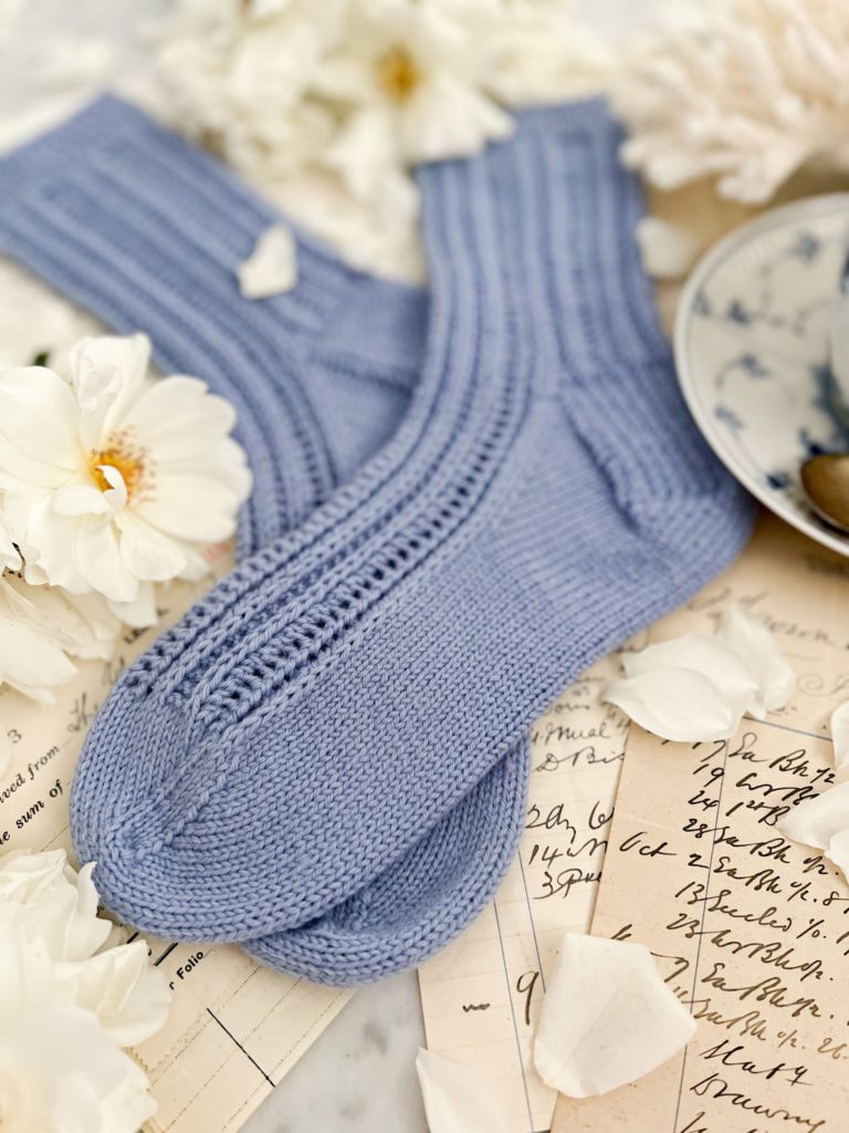 A close up on the toes of a pair of light blue handknit socks.