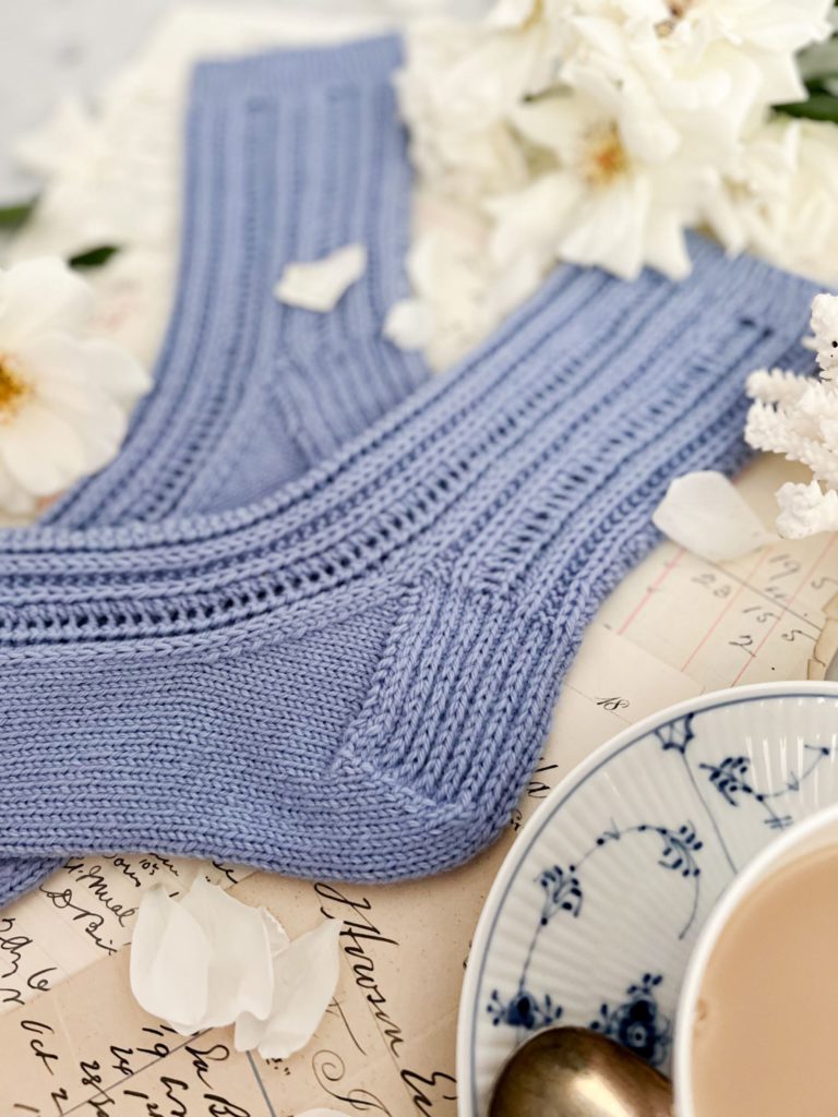 A close up on the heel of a pair of light blue handknit socks.