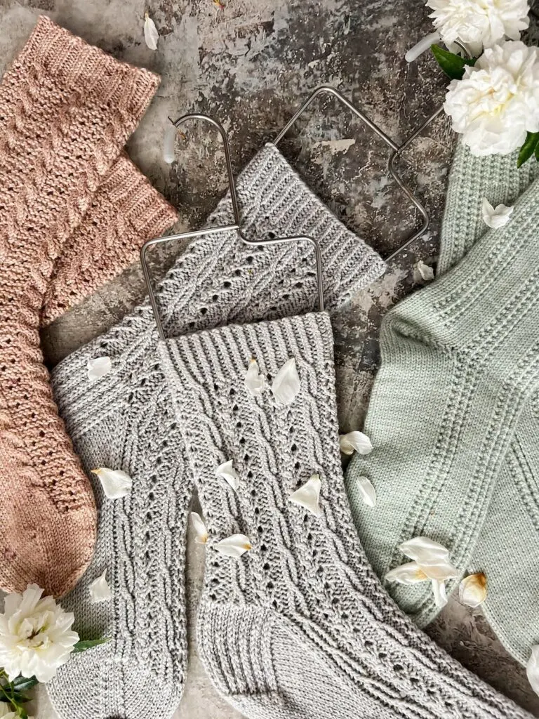 A zoomed-in version of the flatlay photo earlier in this post. It more clearly shows the wire sock blockers on the gray cabled socks, along with portions of the pink and green socks on either side.