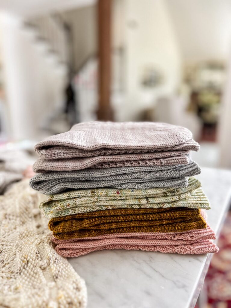 A stack of folded handknit socks in different colors all piled on top of each other.