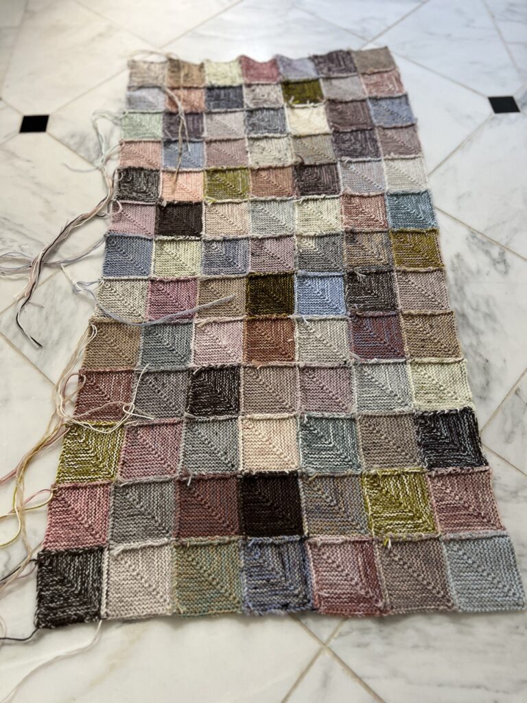 The back side of a mitered square blanket in progress. This shows all the ridged edges where the squares are joined and many of the tails that still need to be woven.