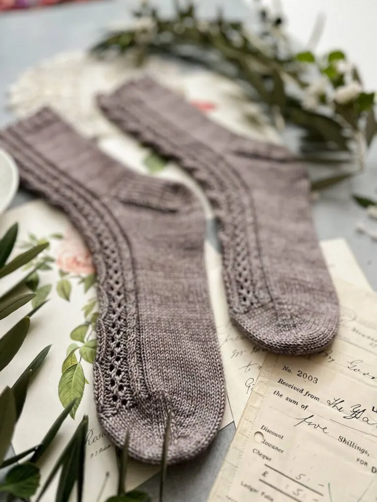 A close-up on the toes of a pair of grayish-purple socks. This shoes the wedge toe construction of the socks.