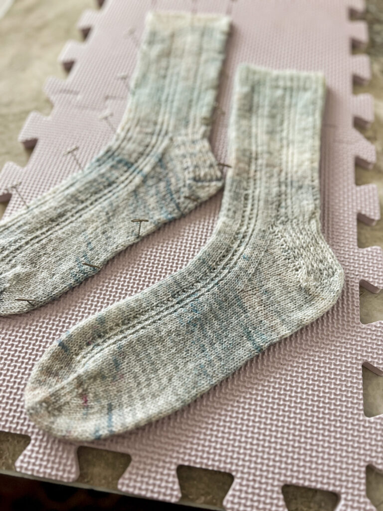 A close up on the foot of a drying sock on some light purple trying mats. This sock has not been pinned into place, but the sock behind it has been.