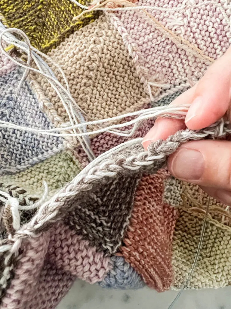 A close-up on the slipped stitch edge of a mitered square. It looks like the strands of yarn have been braided, and each pair of loops represents one slipped stitch.