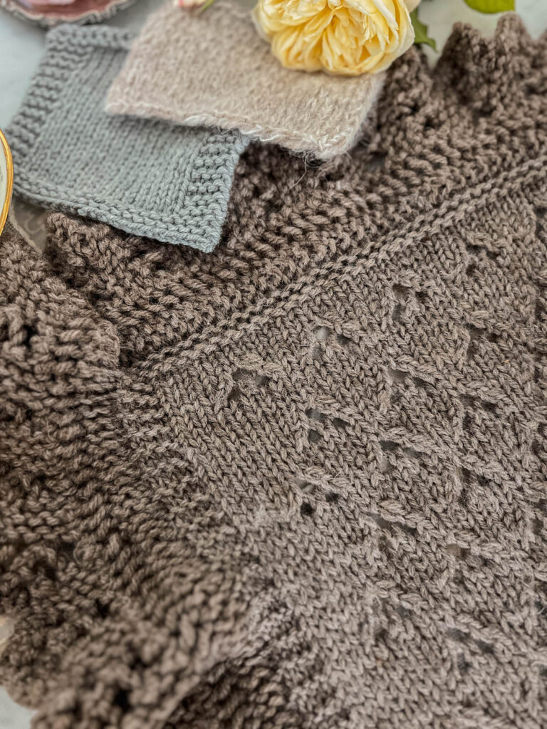A top-down image showing a large piece of stockinette knitting with an elaborate knitted lace border. This border helps keep the stockinette portion of the knitting from curling too badly.