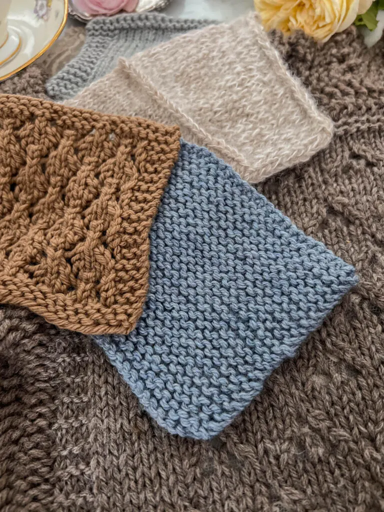 Several swatches of knit fabric in garter stitch, stockinette, and a simple lace stitch are laid flat on a larger piece of stockinette knitting.