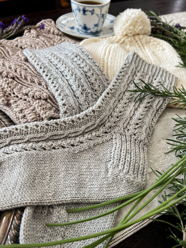 A close-up on a pair of handknit socks, which shows the 1x1x1 twisted cables running the full length of each sock. These cables are created using twisted stitches knit through the back loop.