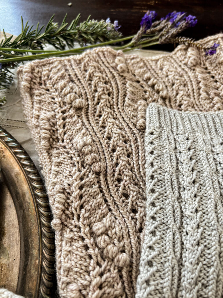 A close-up on the leg of a handknit sock and a handknit cowl, both of which use twisted stitches knit through the back loop to create intensely sculptural stitch patterns.