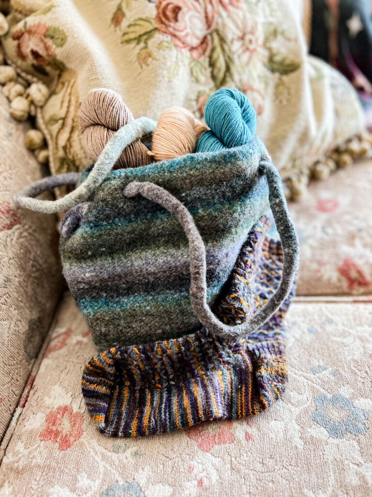 A felted, striped purse full of yarn and a knit sock with some minor felting.