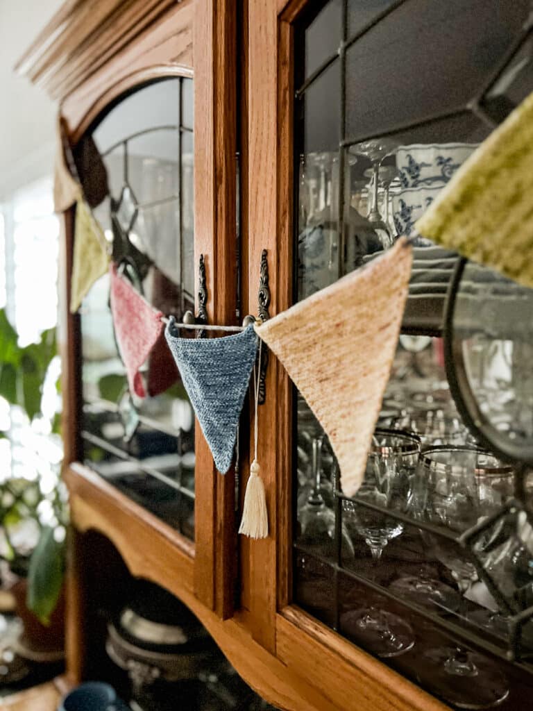 A close-up on a couple of the triangles in a string of triangle bunting across the front doors of a vintage oak china hutch.
