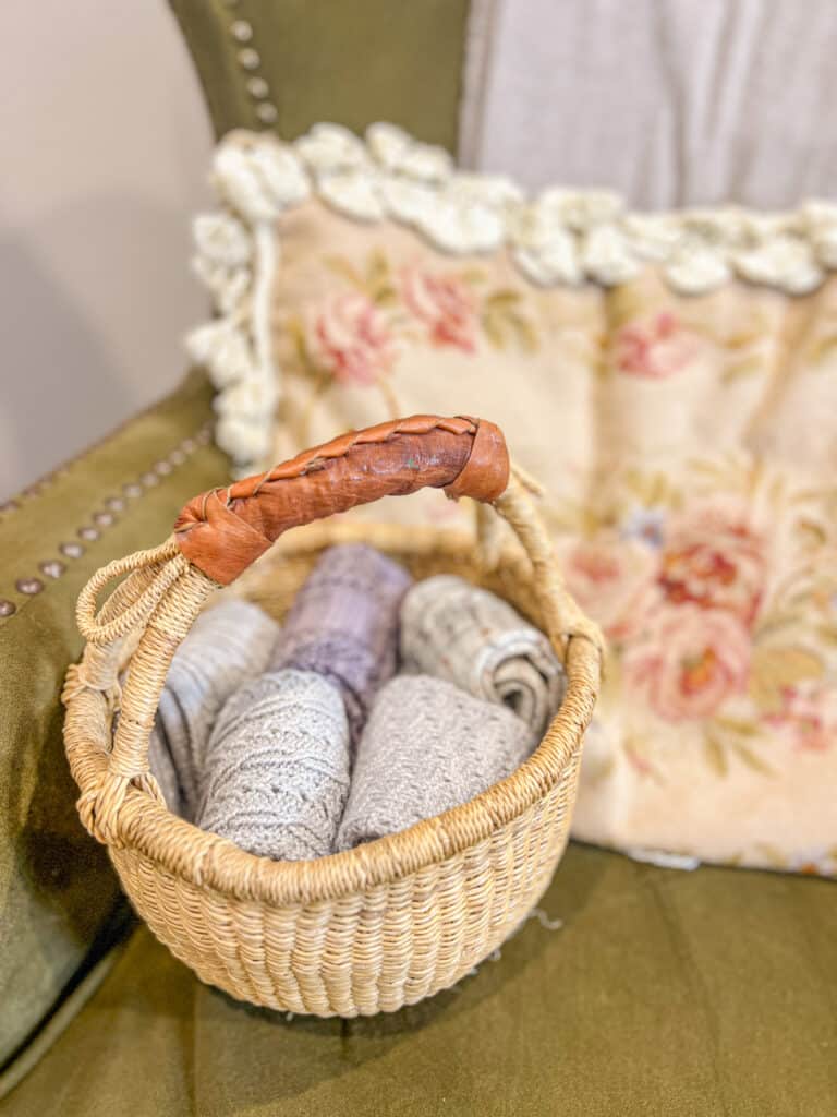A small, handwoven basket holds five pairs of folded, handknit socks with lots of texture on the legs.