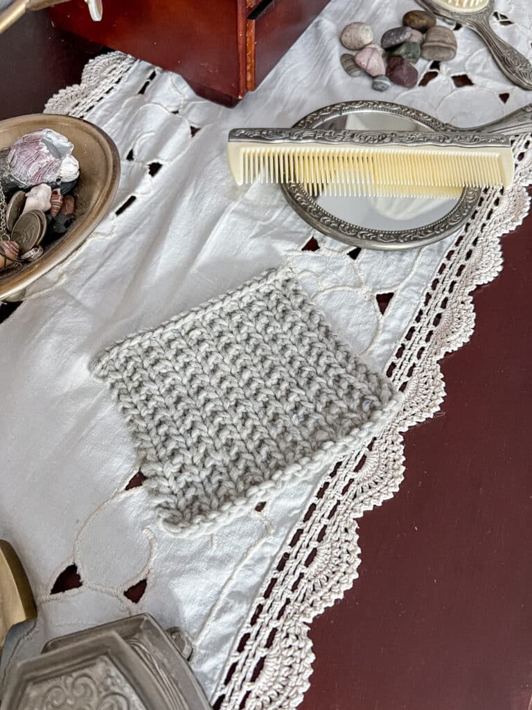 A large, gray swatch of broken rib sits on a dark wood dresser surrounded by vintage trinkets and pretty pebbles from the beach.