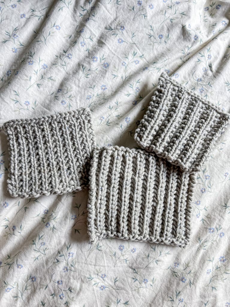 Three gray swatches of fisherman's rib, broken rib, and mistake rib are arranged on a pastel floral duvet cover.