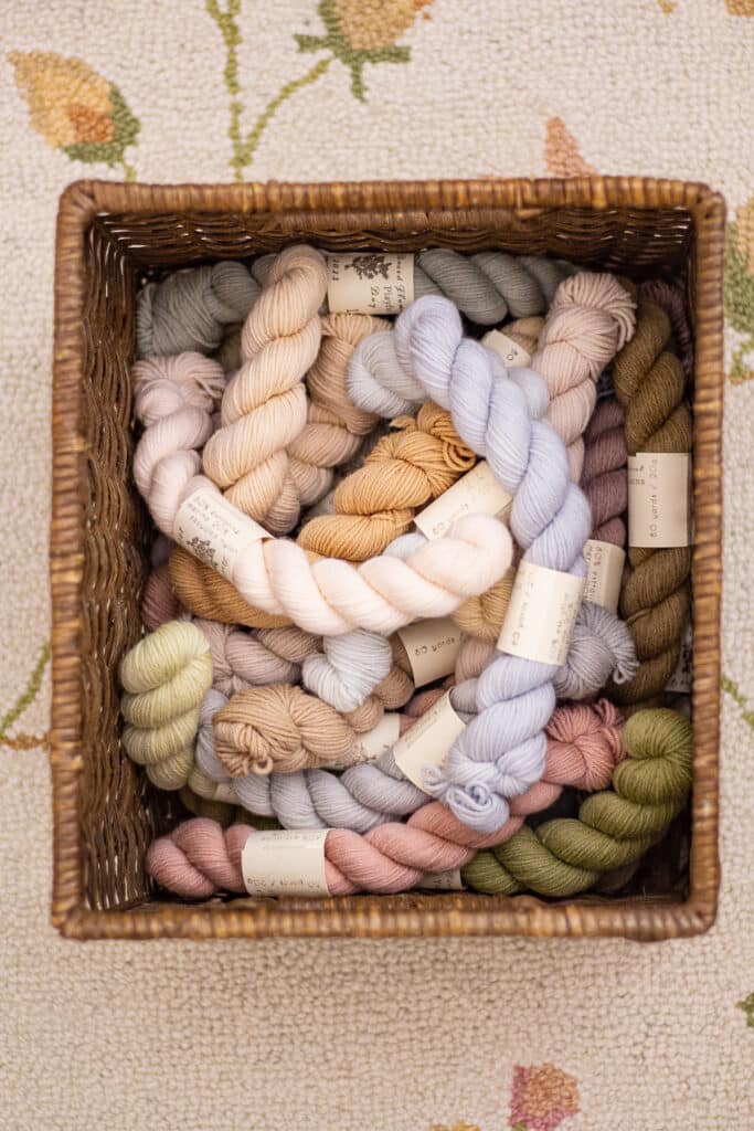 A top-down photo of a basket full of pastel mini skeins of yarn.