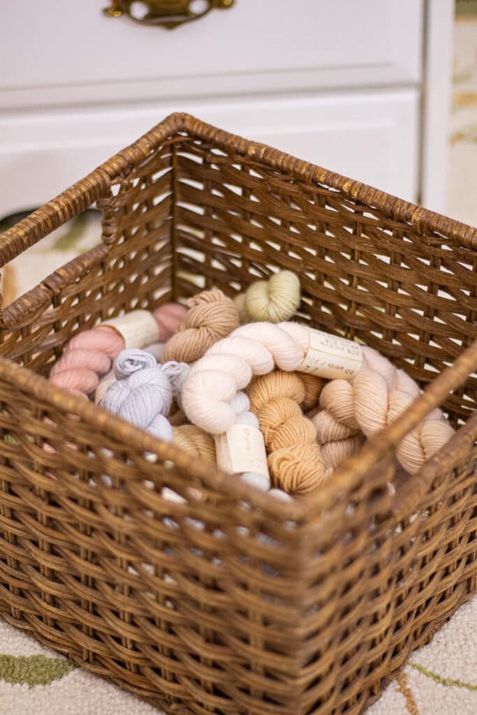A side-angle photo of a basket full of pastel mini skeins of yarn.