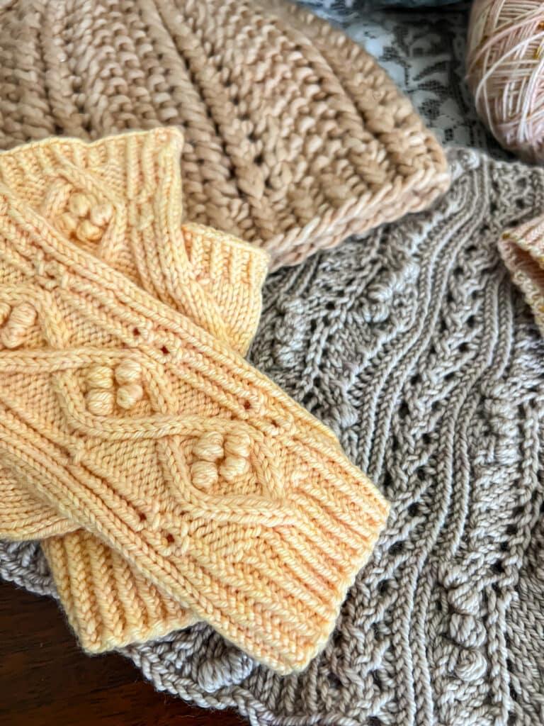 A close-up photo of a pair of yellow fingerless mitts that use twisted stitches in the ribbing and along the length of the mitts as a design element.