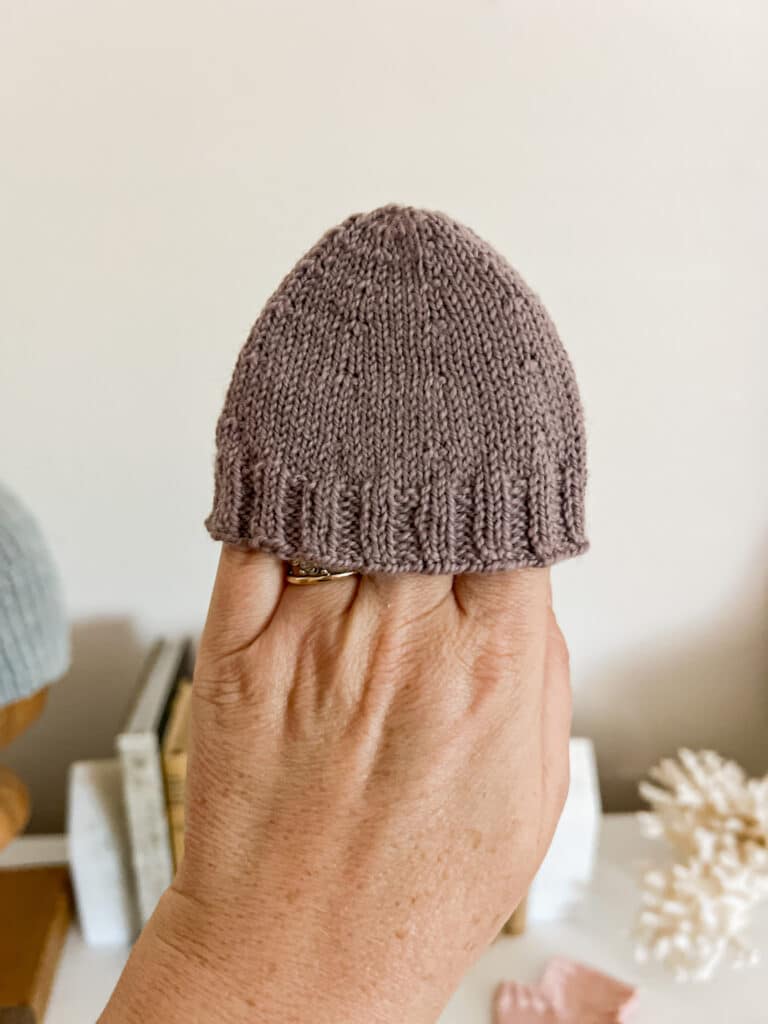 A white woman's left hand wears a purple swatch of a sock toe on the fingertips.